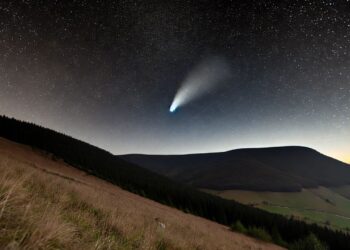 Kométa Tsuchinshan-ATLAS s jemným žiarivým chvostom na nočnej oblohe nad slovenskou krajinou, s horskou krajinou a hviezdnou oblohou v pozadí.