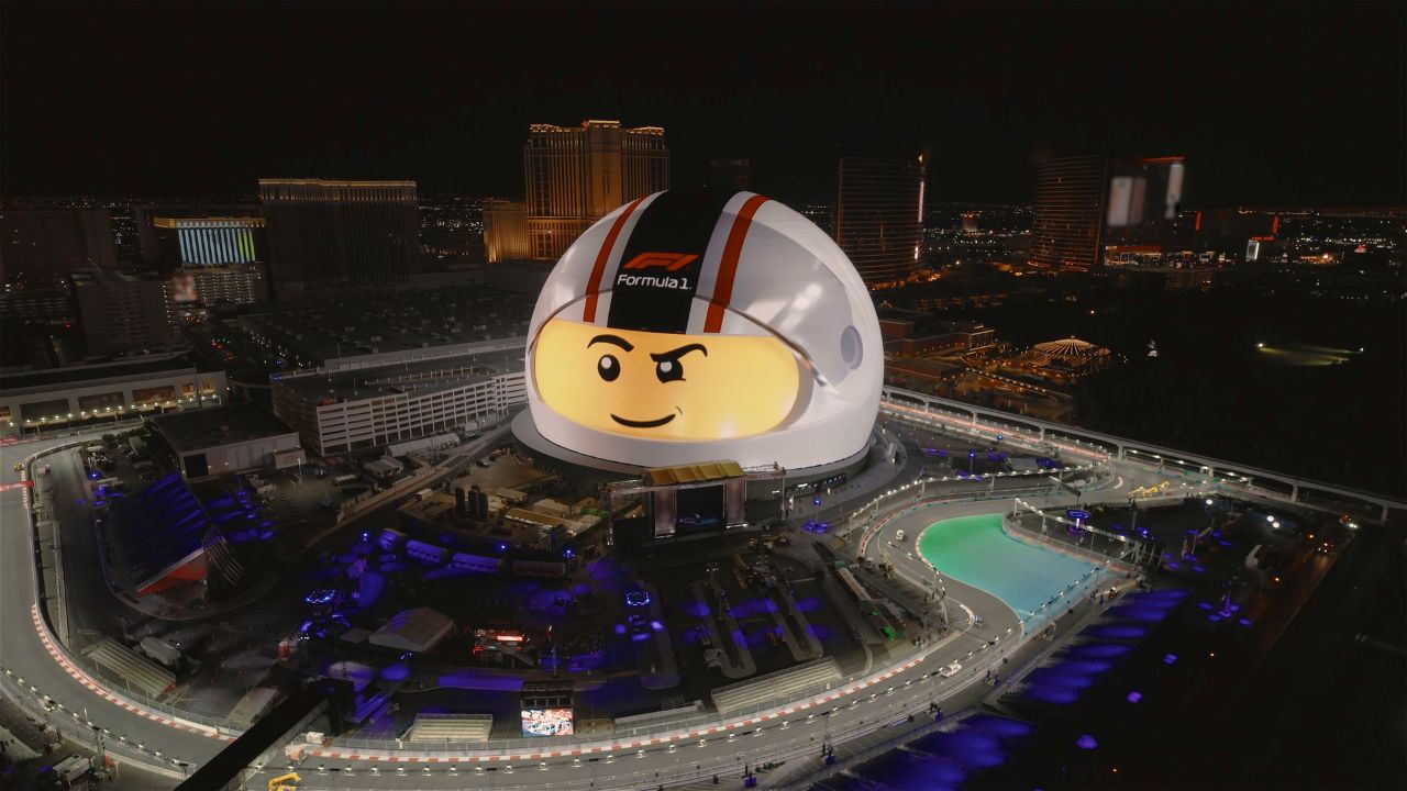 Obrovská LEGO prilba premietnutá na Exosphere – LED displeji na vonkajšej strane Sphere v Las Vegas počas FORMULA 1® LAS VEGAS GRAND PRIX 2024, s mestskou panorámou v pozadí.