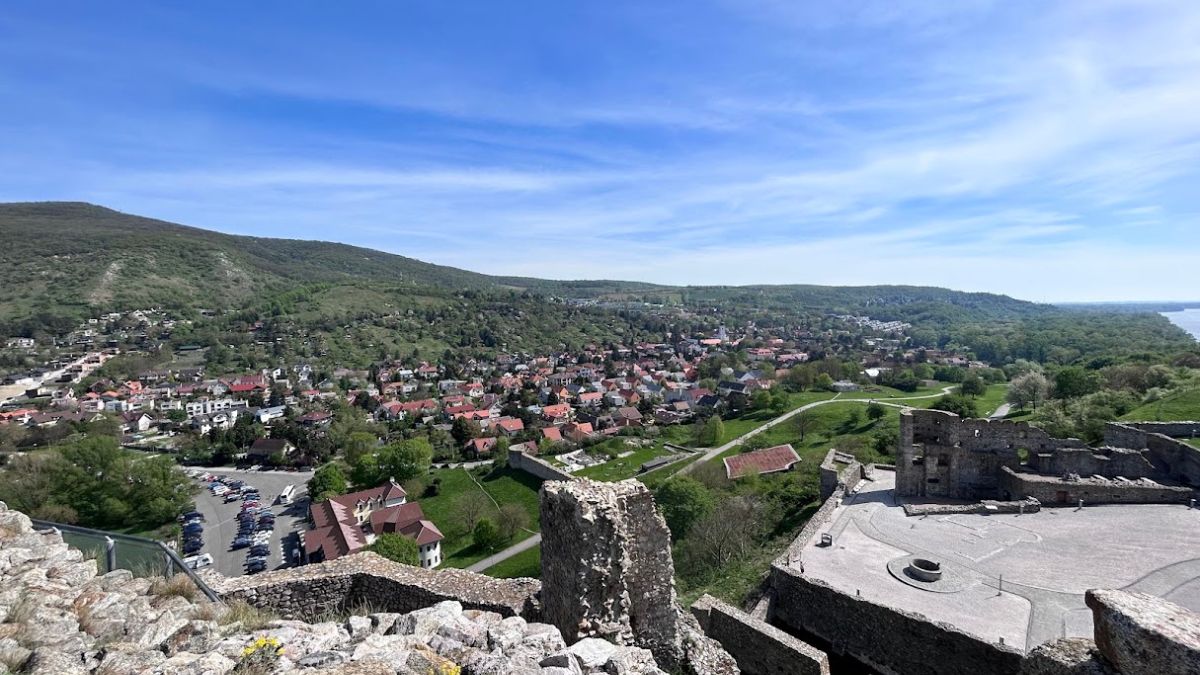 Pohľad z hradu Devín na okolité dediny, zeleň a rieku Morava pod modrou oblohou.