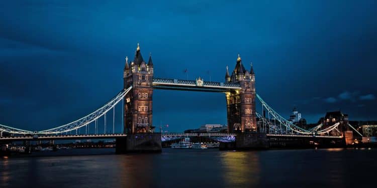 Večerný pohľad na osvetlený Tower Bridge v Londýne s tmavomodrou oblohou v pozadí.