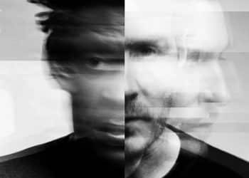 Čiernobiely umelecký portrét dvoch členov skupiny Massive Attack s efektom rozmazania a prekrývania tvárí, zachytávajúci ich mystickú a melancholickú atmosféru.